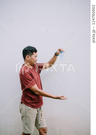 Man contemplates squashed water bottle against a clean white backdrop 124760802