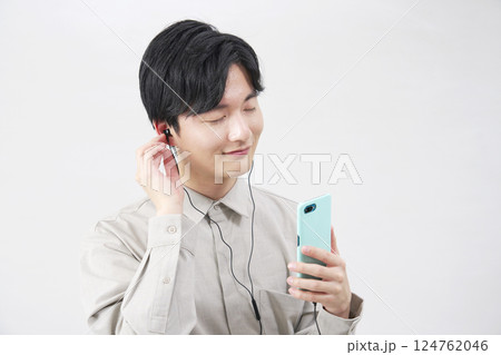 イヤホンをつけて音楽を聴く20代男性 白背景 イヤホンをつけて音楽を聴く20代男性 白背景 124762046