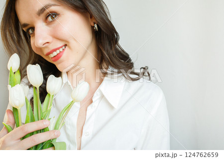 Smiling young woman brunette with white tulips portrait close up with copy space 124762659