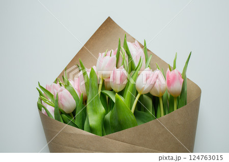 Pink tulips bouquet wrapped in brown craft paper on white background 124763015