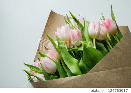 Pink tulips bouquet wrapped in brown craft paper close up 124763017