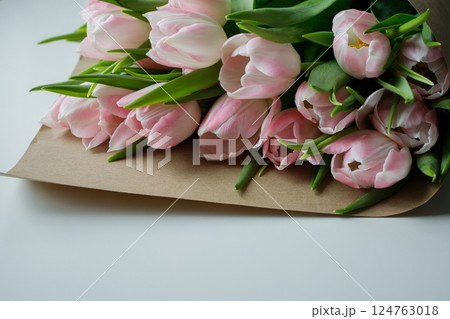 Pink tulips bouquet wrapped in brown craft paper on white background close up 124763018