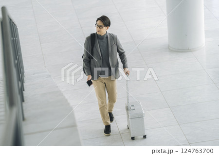 キャリーバッグとスマホを持って歩く40代の男性 124763700