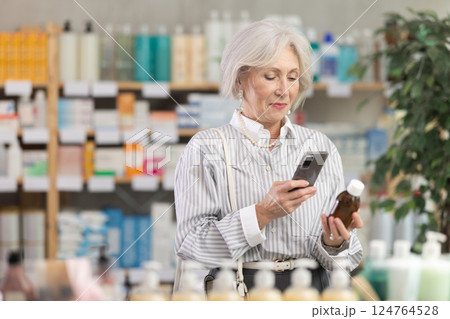 Elderly woman scanning qr code of syrup 124764528