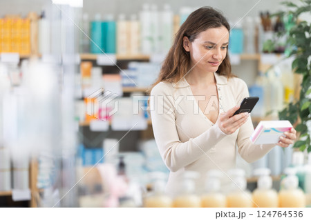 Woman in pharmacy scans QR code on pills box 124764536