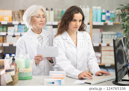 Two female pharmacists employee using computer 124765106