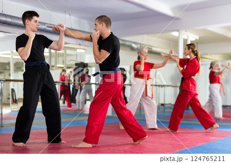Two men training in sparring at karate training in gym Two men training in sparring at karate training in gym 124765211