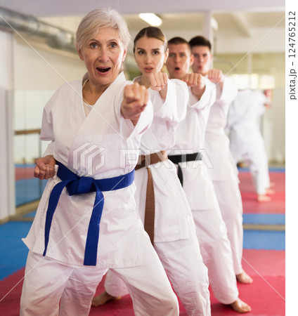 Aged woman practicing martial arts with group in gym 124765212