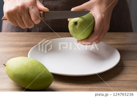 Hand holding kitchen knife and cutting green mango to making salad 124765236
