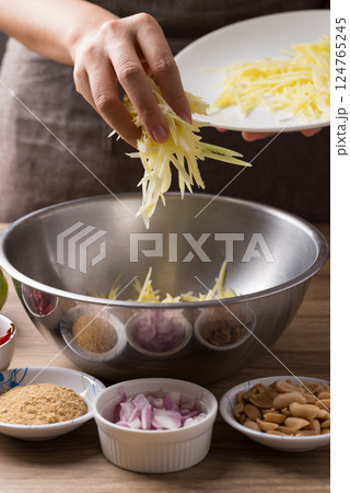 Spicy mango salad cooking, Hand pouring shredded green mango in bowl and mixing with ingredients Spicy mango salad cooking, Hand pouring shredded green mango in bowl and mixing with ingredients 124765245