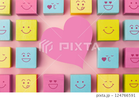 Love and Human Relationship Concepts. Happy Community. Pastel Pink Heart Shape surrounded by Group of Smiling Emoticon Diversity Face on Cube. Table Top View Love and Human Relationship Concepts. Happy Community. Pastel Pink Heart Shape surrounded by Group of Smiling Emoticon Diversity Face on Cube. Table Top View 124766591