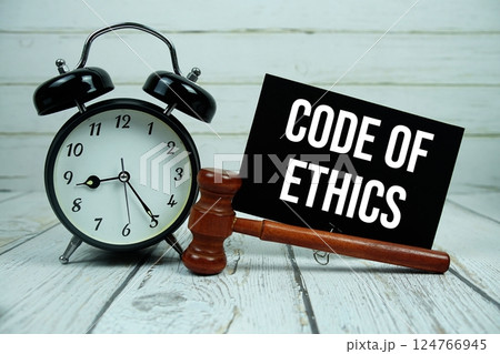Code of Ethics text on paper card with alarm clock and wooden judge gavel on wooden background 124766945