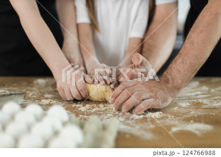 Caucasian family bonding through cooking activity, kneading dough with children and adults together 124766988