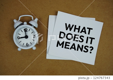 What does it mean? text on sticky note with alarm clock on paper craft background What does it mean? text on sticky note with alarm clock on paper craft background 124767343