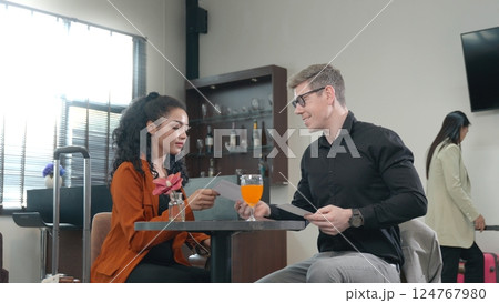 Two elegant partners sitting in airport lounge or waiting room, businessman and woman with suitcase come to meeting and talking together on business travelers waiting their flight at airport terminal 124767980