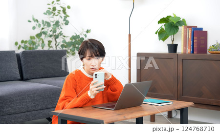 スマホとノートパソコンを見ながら悩むミドルエイジ女性 124768710