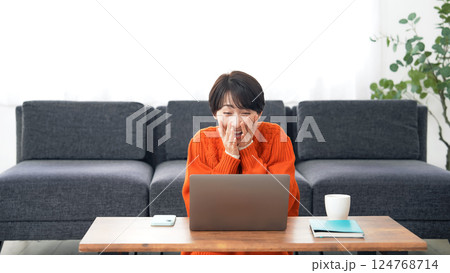 ノートパソコンでライブ配信を見ながら拍手するミドル女性 124768714