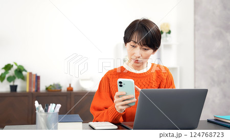 スマホとノートパソコンを使うミドル女性 スマホとノートパソコンを使うミドル女性 124768723
