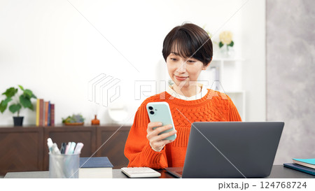 スマホとノートパソコンを使うミドル女性 124768724