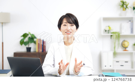 カメラ目線で会話する白衣のミドル女性 カメラ目線で会話する白衣のミドル女性 124768738