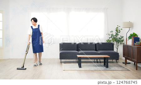 部屋の床に掃除機をかけるエプロンをつけたミドル女性 部屋の床に掃除機をかけるエプロンをつけたミドル女性 124768745