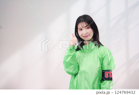 スタッフジャンパーをきた笑顔のイベントスタッフ（シンプル背景） 124769432