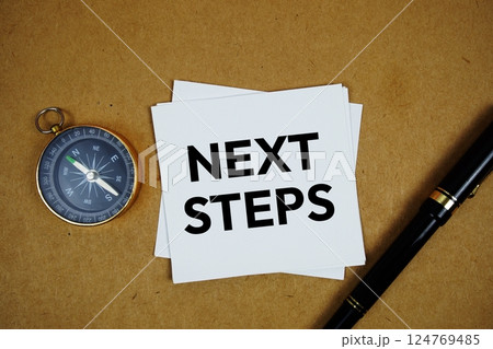 Next Steps text on sticky note with compass and pen on paper craft background 124769485