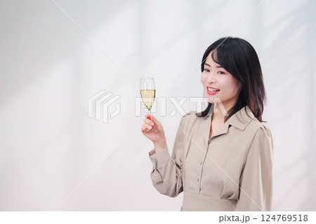 笑顔でスパークリングワインを飲む若い女性(シンプル背景) 笑顔でスパークリングワインを飲む若い女性(シンプル背景) 124769518