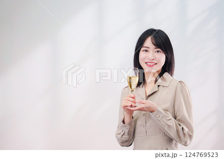 笑顔でスパークリングワインを飲む若い女性(シンプル背景) 笑顔でスパークリングワインを飲む若い女性(シンプル背景) 124769523