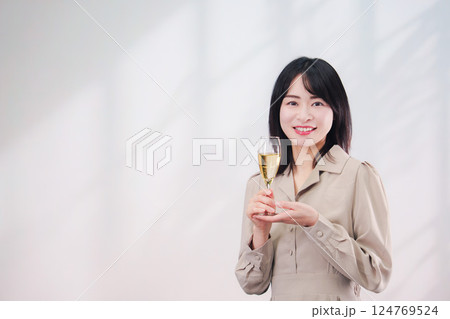 笑顔でスパークリングワインを飲む若い女性(シンプル背景) 笑顔でスパークリングワインを飲む若い女性(シンプル背景) 124769524