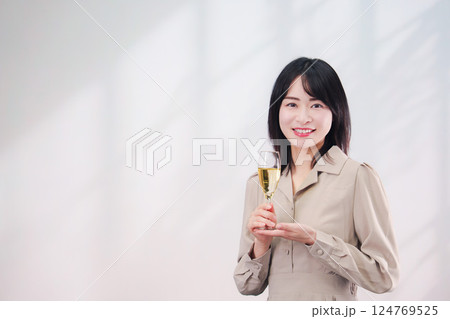 笑顔でスパークリングワインを飲む若い女性（シンプル背景） 124769525