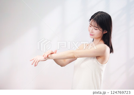 腕にクリームを塗る若い女性(シンプル背景) 腕にクリームを塗る若い女性(シンプル背景) 124769723