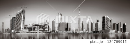 Monochrome city skyline with tall skyscrapers reflecting on calm water under a cloudy sky, Dubai Marina bay UAE Monochrome city skyline with tall skyscrapers reflecting on calm water under a cloudy sky, Dubai Marina bay UAE 124769915
