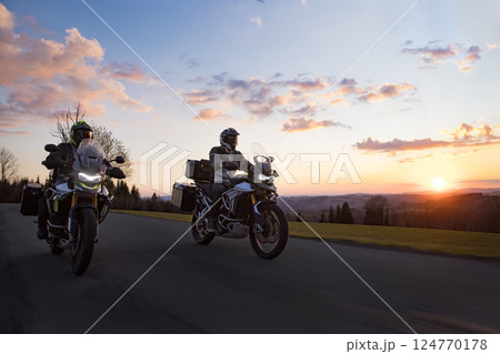 Drivers riding motorcycle on empty road during sunset, spring mountains 124770178