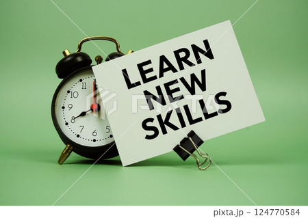 Learn New Skills text message on paper card with alarm clock on green background Learn New Skills text message on paper card with alarm clock on green background 124770584