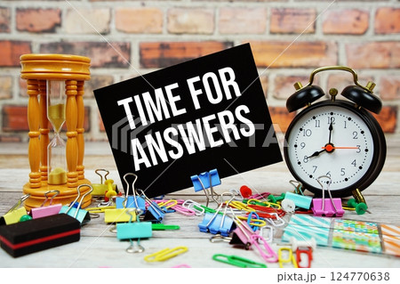 Time For Answers text on paper card with alarm clock and stationary on wooden background 124770638