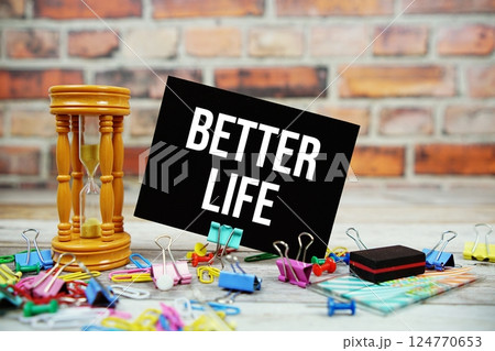 Better Life text on paper card with hourglass and stationary on wooden background Better Life text on paper card with hourglass and stationary on wooden background 124770653