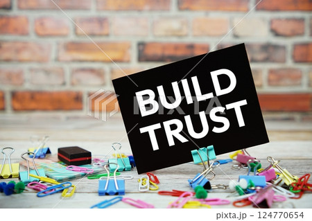 Build Trust text on paper card with stationary on wooden background Build Trust text on paper card with stationary on wooden background 124770654