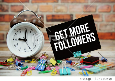 Get More Followers text on paper card with alarm clock and stationary on wooden background Get More Followers text on paper card with alarm clock and stationary on wooden background 124770656