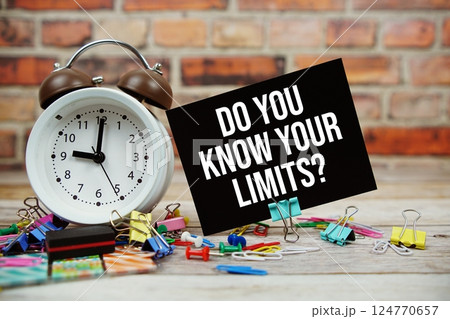 Do You Know Your Limits? text on paper card with alarm clock and stationary on wooden background 124770657