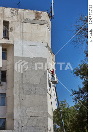 Worker using a cherry picker for renovation work on the building's facade Worker using a cherry picker for renovation work on the building's facade 124771713