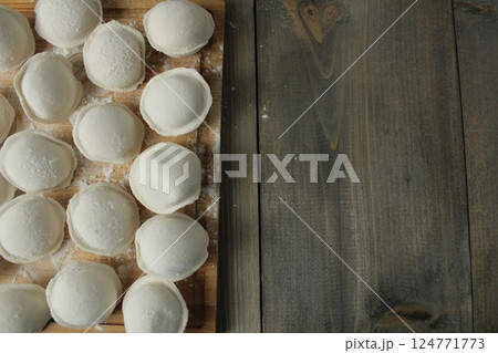 Raw uncooked dumplings on a board with space for copyspace text. Background concept for reception Raw uncooked dumplings on a board with space for copyspace text. Background concept for reception 124771773