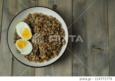 boiled buckwheat and two halves of an egg with a bright yolk in a bowl on a gray background with space for the text of the Space vid Serhu boiled buckwheat and two halves of an egg with a bright yolk in a bowl on a gray background with space for the text of the Space vid Serhu 124771779