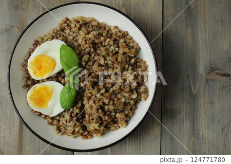 buckwheat porridge egg basil greens in a bowl on a gray fnon with copyspace space for text. Concept of new useful products 124771780