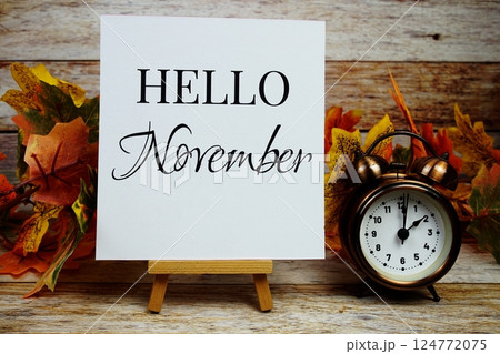 Hello November text with alarm clock and maple leaf decoration on wooden background 124772075