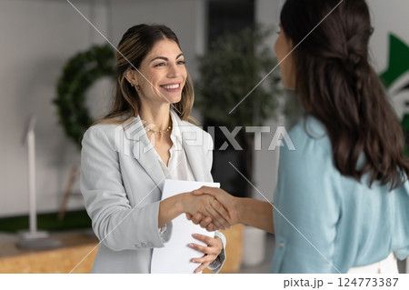 Happy Latin business leader woman giving handshake to female consultant 124773387