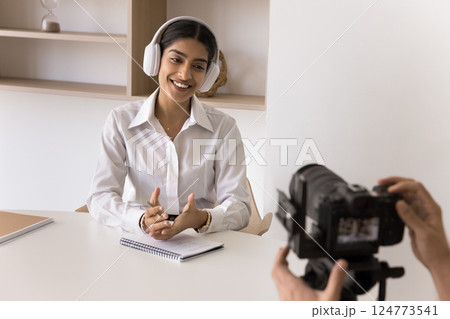 Indian woman wearing headphones engaged in video recording session Indian woman wearing headphones engaged in video recording session 124773541