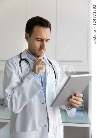 Thoughtful doctor analyzing received patient health test results using tablet 124773592