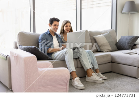 Latin couple sitting with laptop on comfortable sofa 124773731