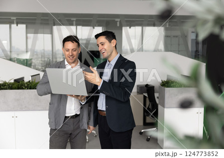 Two happy male business colleagues talking at laptop 124773852